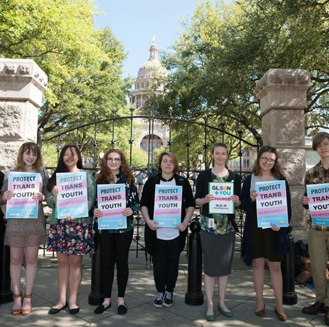 A row of seven students stands in front of a state capital holding GLSEN signs that read: Protect Trans Youth.
